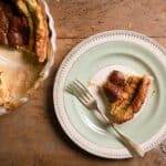 A slice of Blue Cheese Soufflé Tart on a plate and the rest of the tart on the side