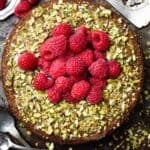 pistachio raspberry cake with a cake server and spoons on the side