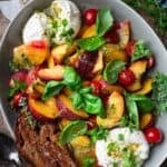 peach Caprese salad with burrata and basil salad dressing in a bowl with a glass of wine on the side