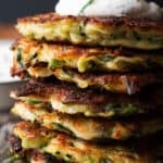 pile of zucchini and feta fritters with a dollop of garlic yogurt on top