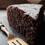 a slice of almond flour chocolate cake on a slate plate and a fork