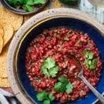 salsa fresca in a bowl with tortilla chips and a glass of wine on the side