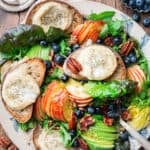 goat cheese salad with arugula, apple, blueberries and pecans in a serving plate with blueberries and goat cheese on the side