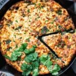 spinach feta frittata in a cast iron skillet with one slice cut out