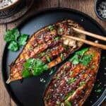 miso glazed eggplant with chopsticks in black plate.