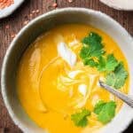 red lentil carrot soup with cilantro and coconut yogurt in a bowl.