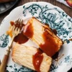 two slices of invisible apple cake drizzled with caramel sauce on a vintage plate.