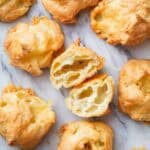 gougères on a marble surface with one gougères cut in half in the center.