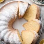 sliced savoy cake in a white serving plate with citrus on the side.