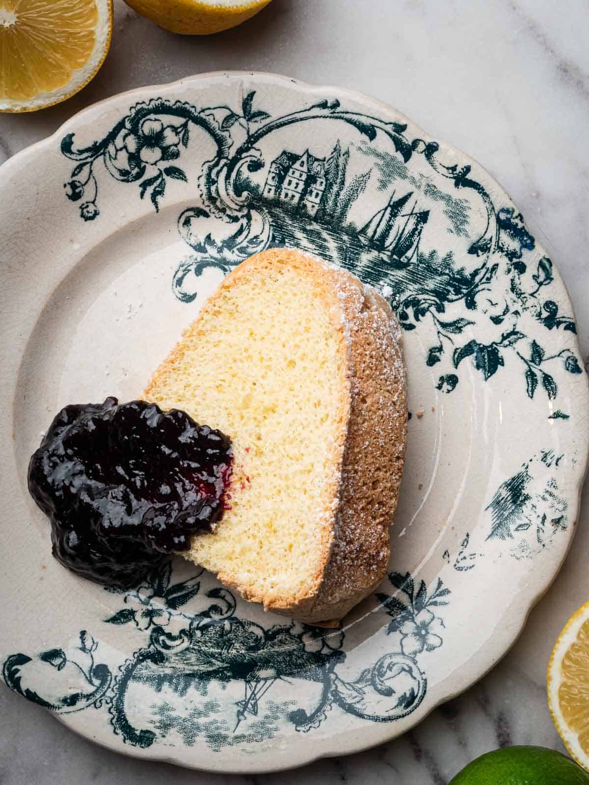 a slice of Savoy cake in a vintage plate with blueberry jam. 
