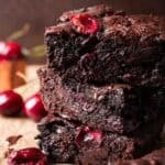 stack of cherry chocolate brownies with roasted cherries on top.