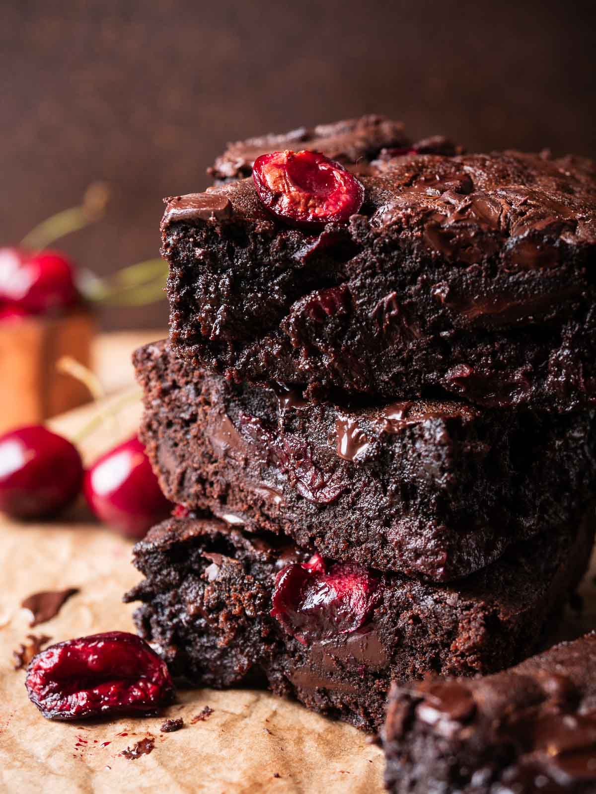 stack of fudgy cherry chocolate brownies with fresh cherries on the background.