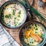 two blue ramekins with French baked eggs topped wth chives and crusty bread.