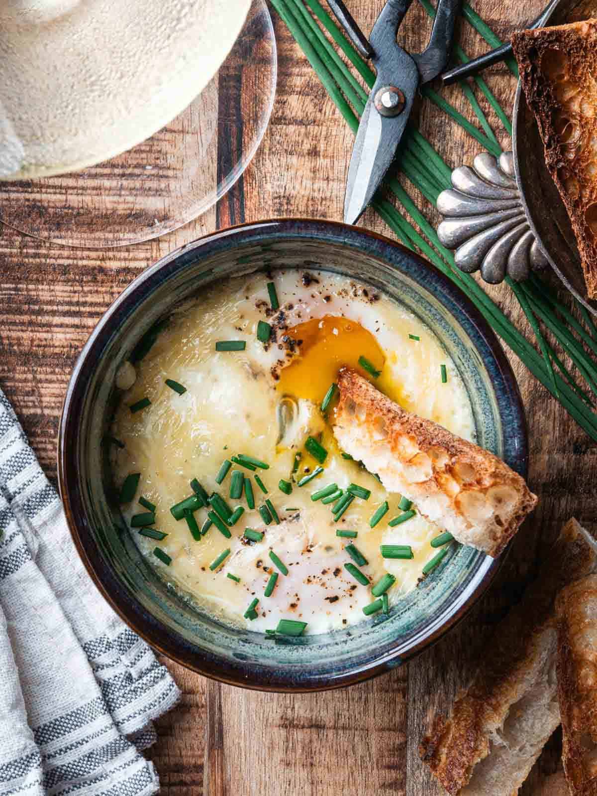 baked eggs with runny yolk and a toasted finger bread in a ramekin.