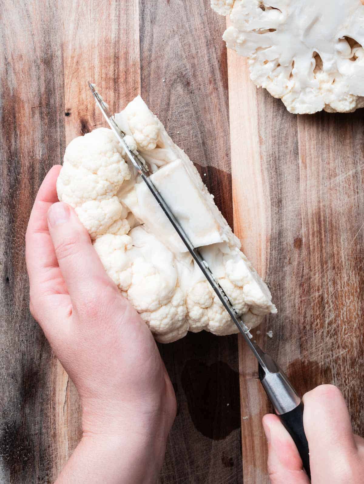 cauliflower steaks cut in a cauliflower head with a kitchen knife.