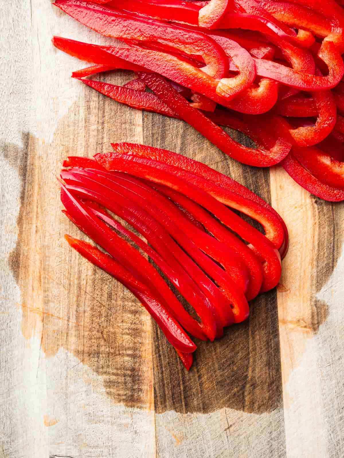 thinly sliced red bell pepper on a wooden board.