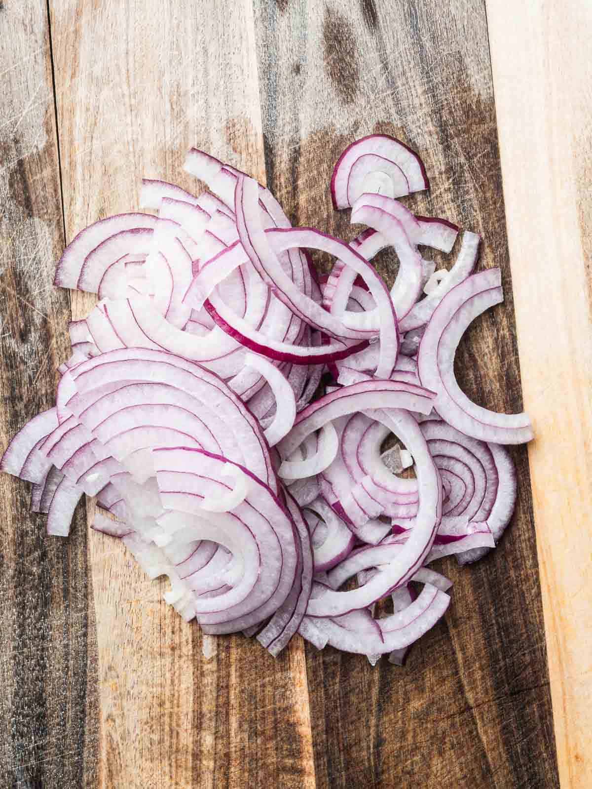 sliced red onions on a wooden board.
