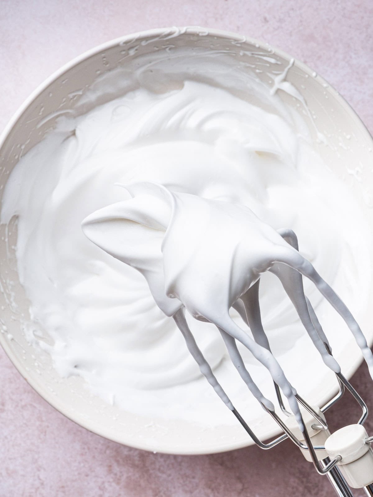 meringue forming stiff peaks on a whisk.