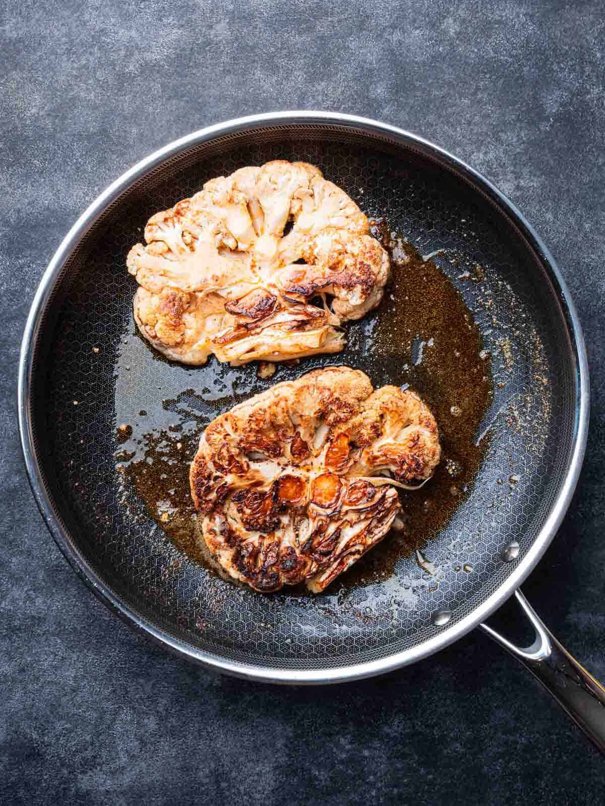 seared cauliflower steaks in a non stick pan.