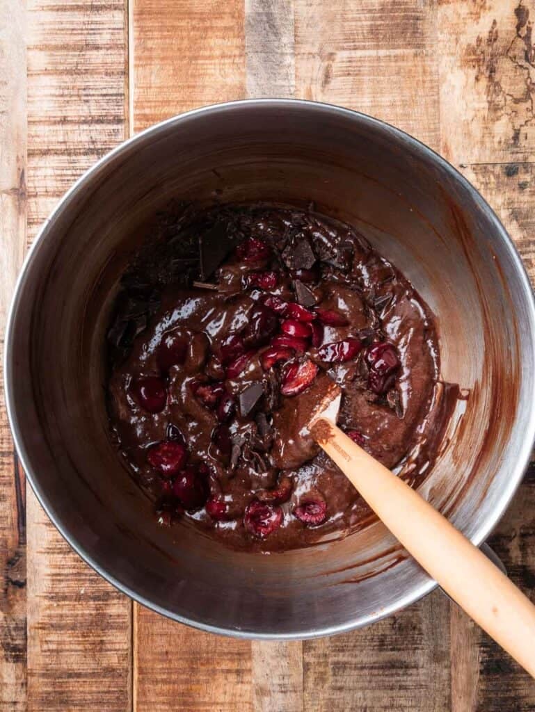 cherry and double chocolate brownies batter in a mixing bowl with a spatula.