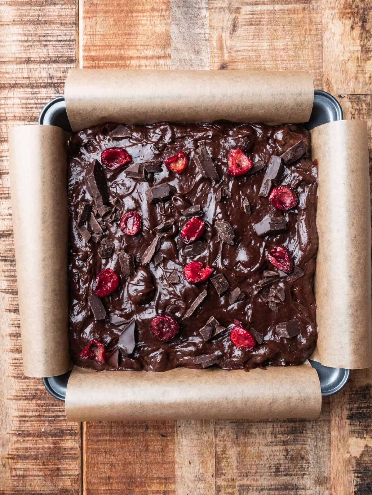 cherry chocolate brownies on a parchment lined square pan.