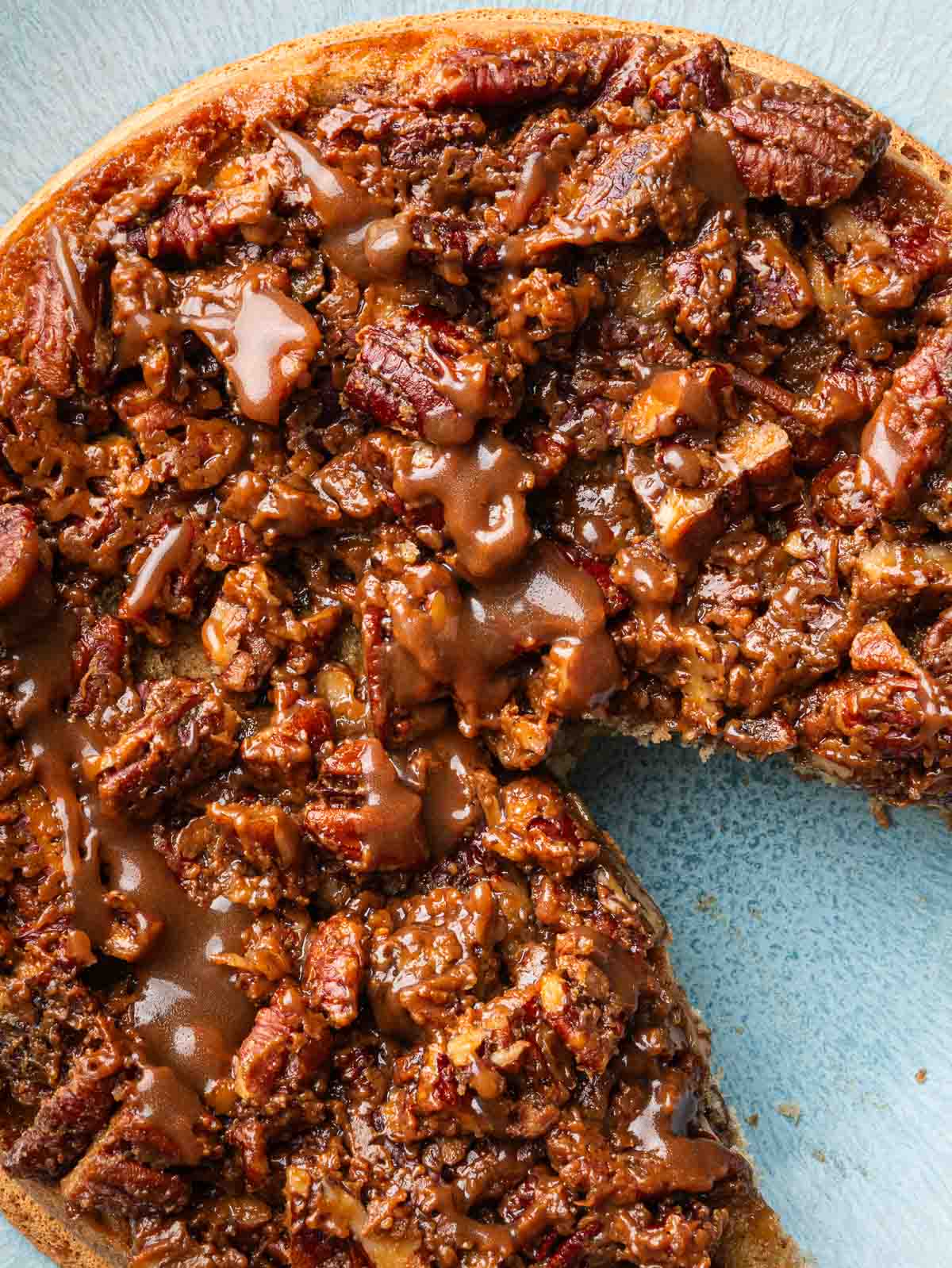 pecan upside down cake with a slice missing on a light blue serving platter.