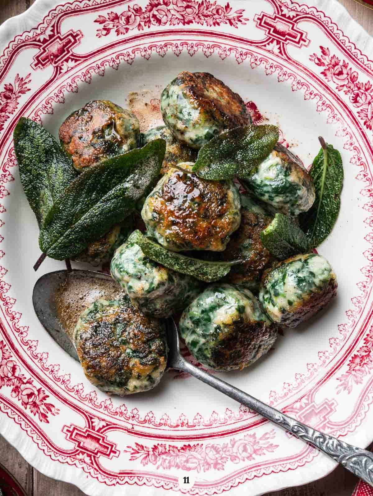 golden gnudi with crispy sage leaves and brown butter in a red and white plate.