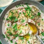 creamy white bean dip in a bowl topped with marinated artichoke hearts, parsley and chili flakes.