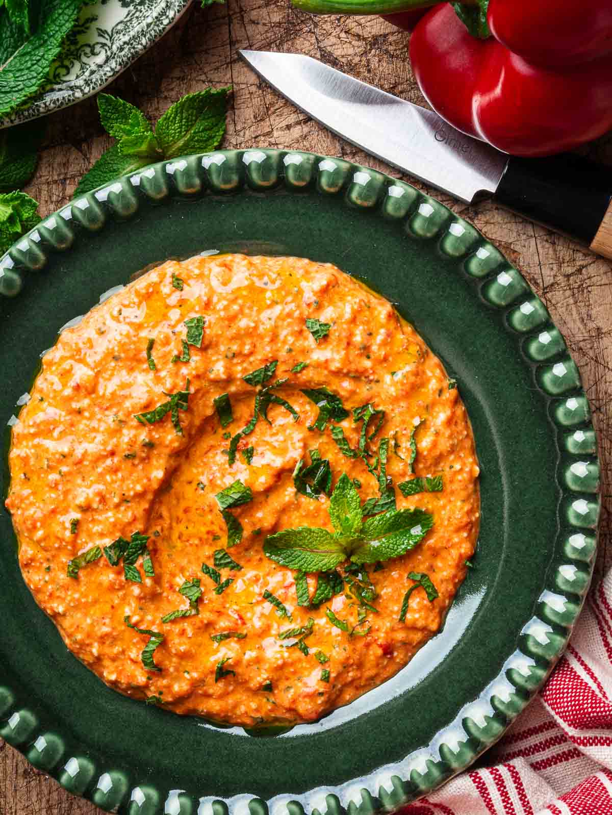 Greek htipiti in a dark green plate, topped with chopped mint. 