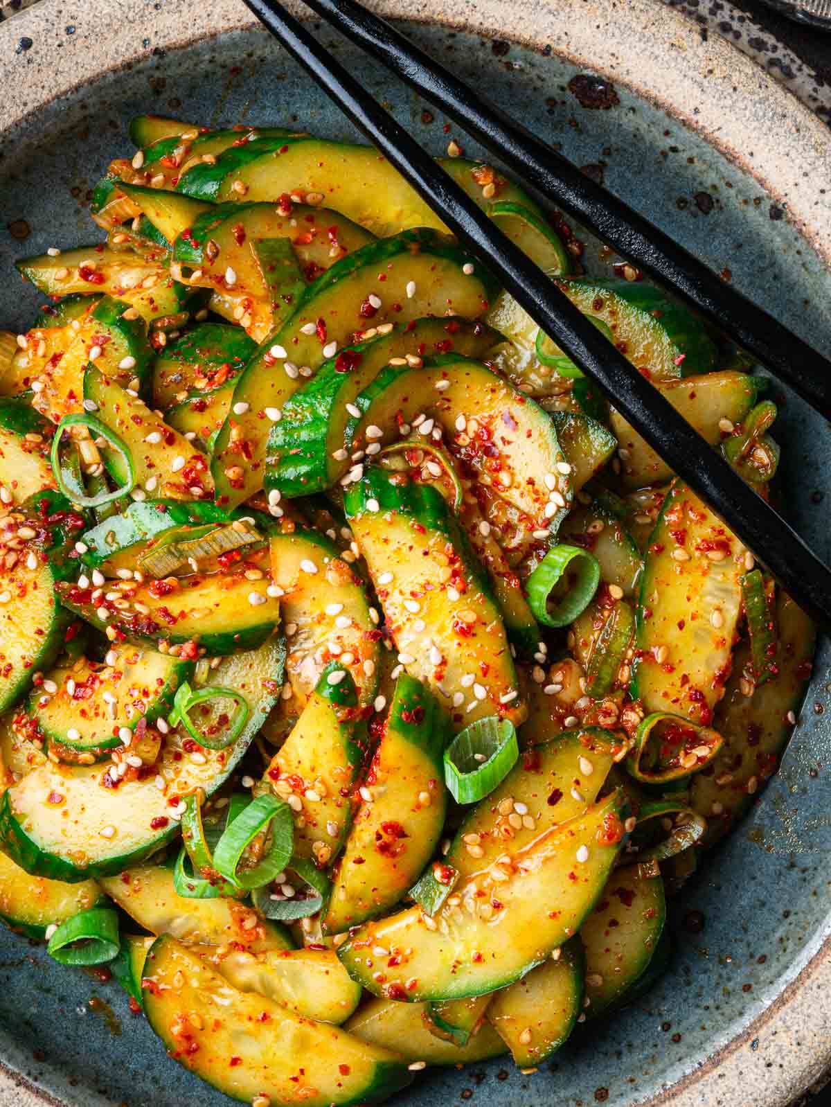 Cucumber banchan sprinkled with sesame seeds in a blue plate.