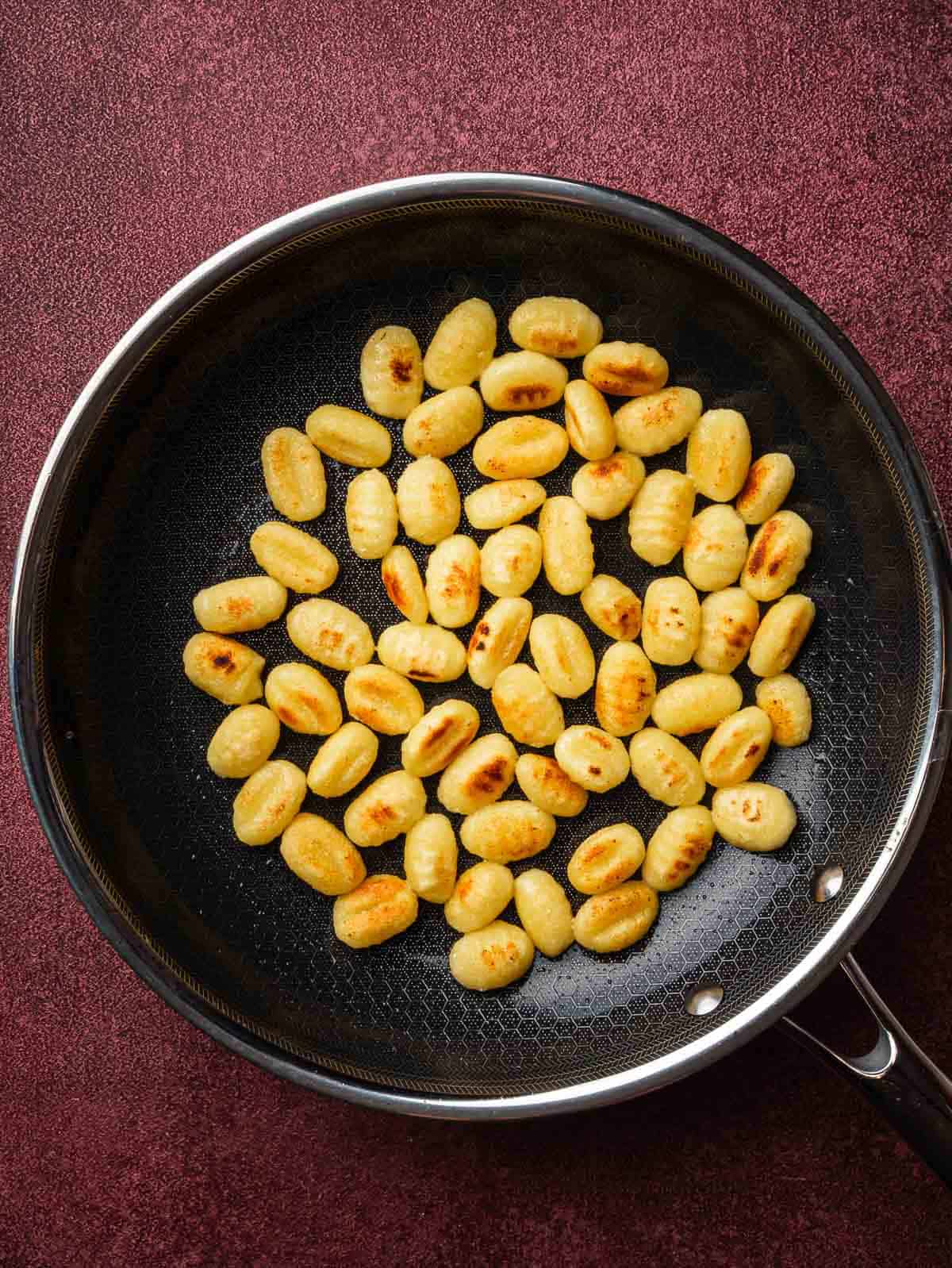 golden gnocchi in a frying pan.