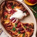 Peach clafoutis with a scoop of vanilla ice cream on top and a slice missing.