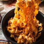 Garlic chili oil noodles held with chopsticks in a black bowl.