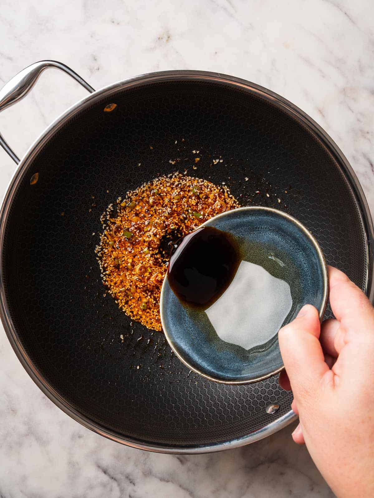 Sauce soy being added to garlic chili oil sauce.