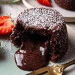 Chocolate lava cake with its heart oozing on a turquoise plate.