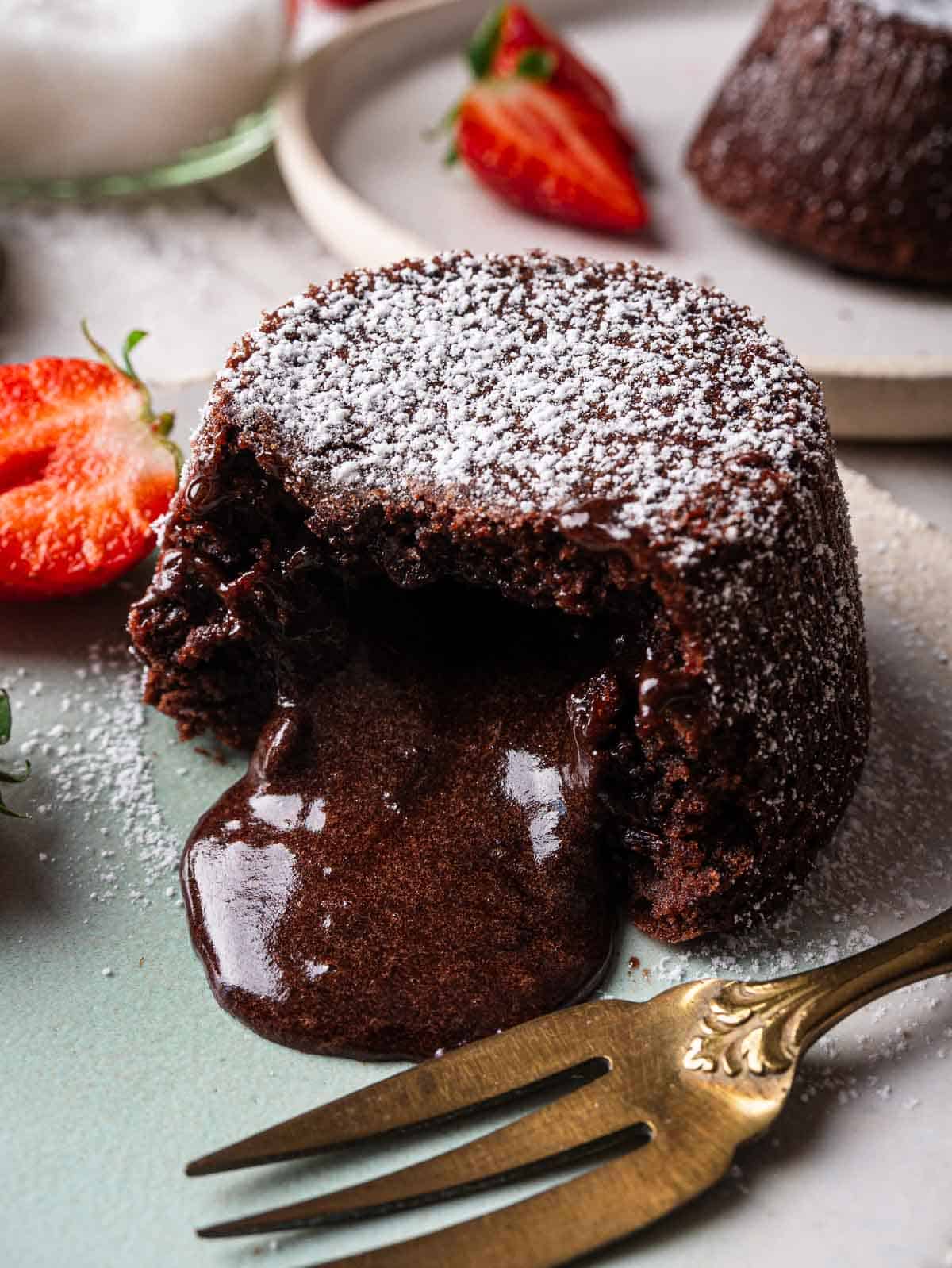 chocolate lava cake with its heart oozing on a turquoise plate.