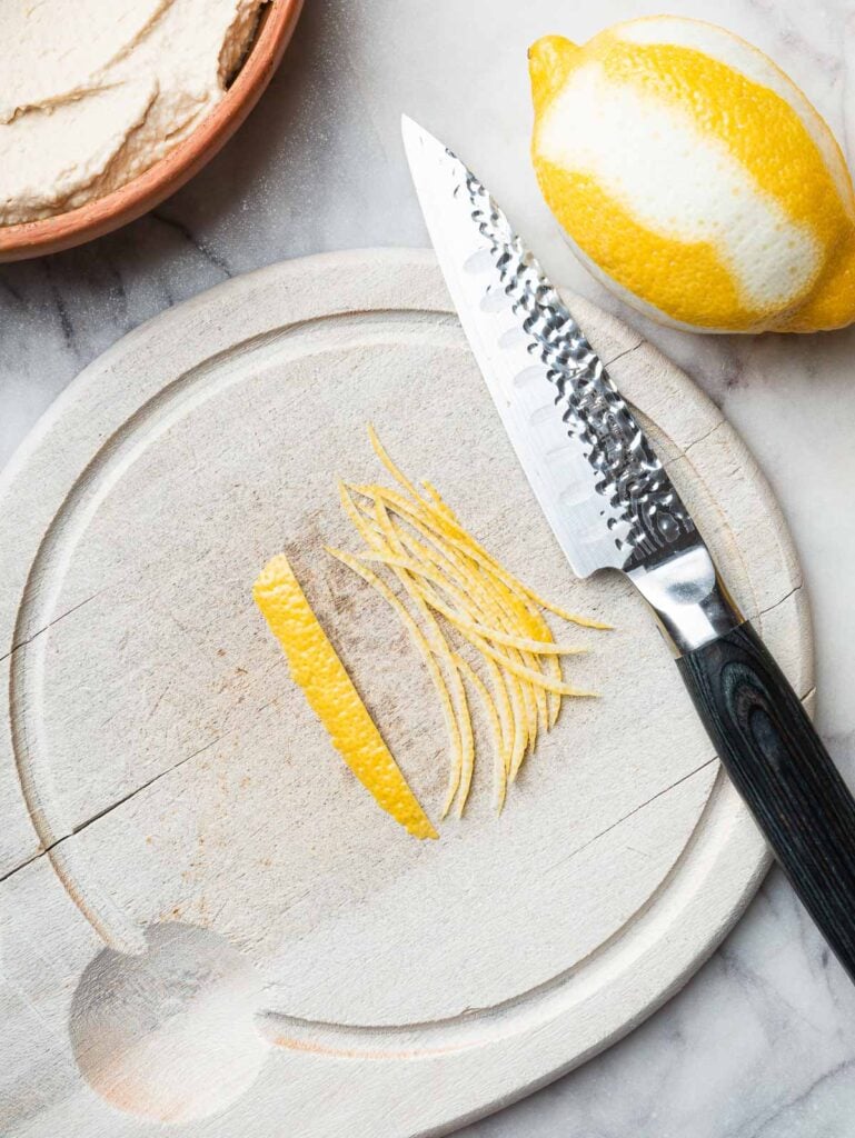 Thin lemon strips on a wooden board.