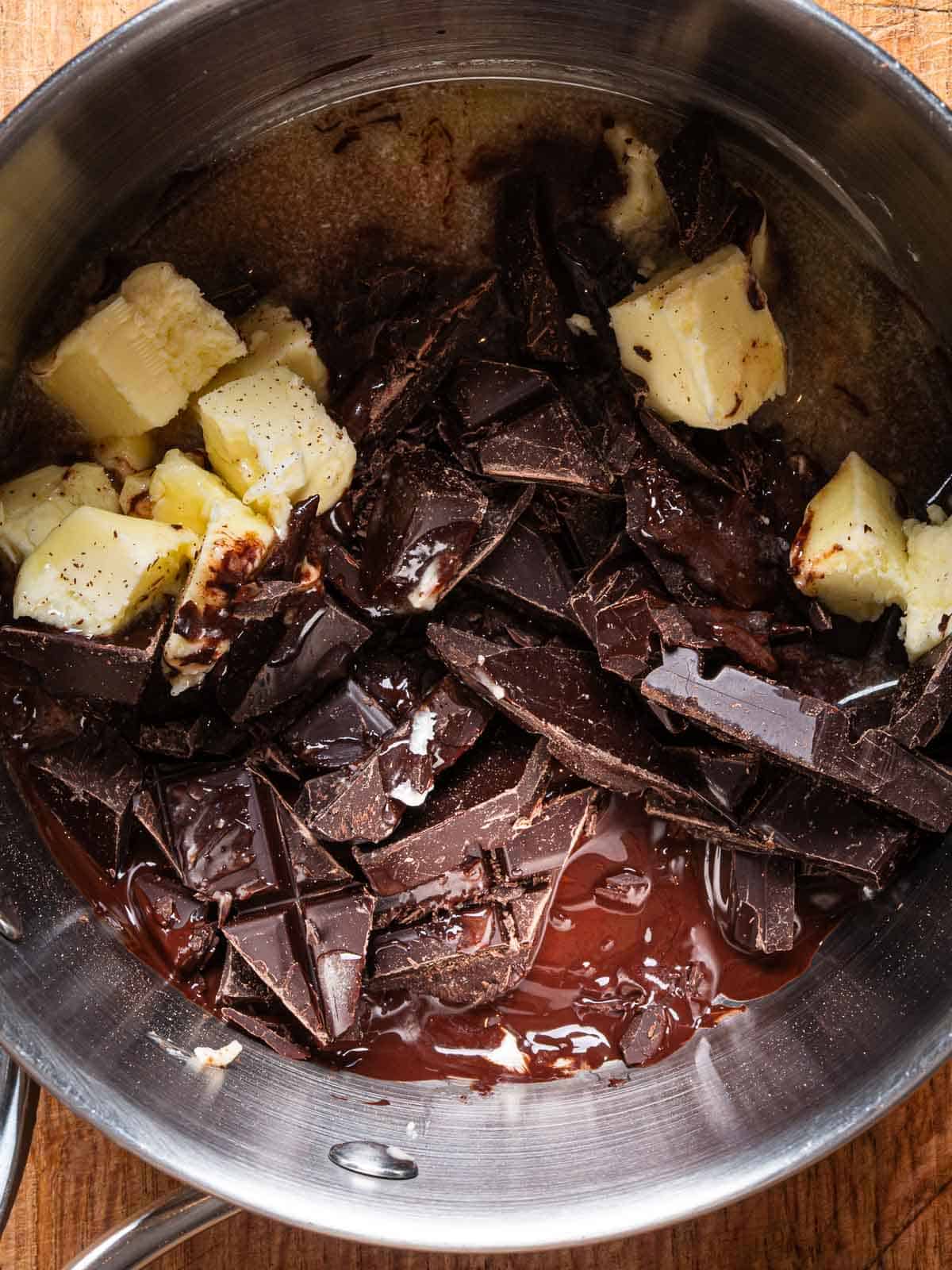 Chopped dark chocolate and butter melting in a saucepan.