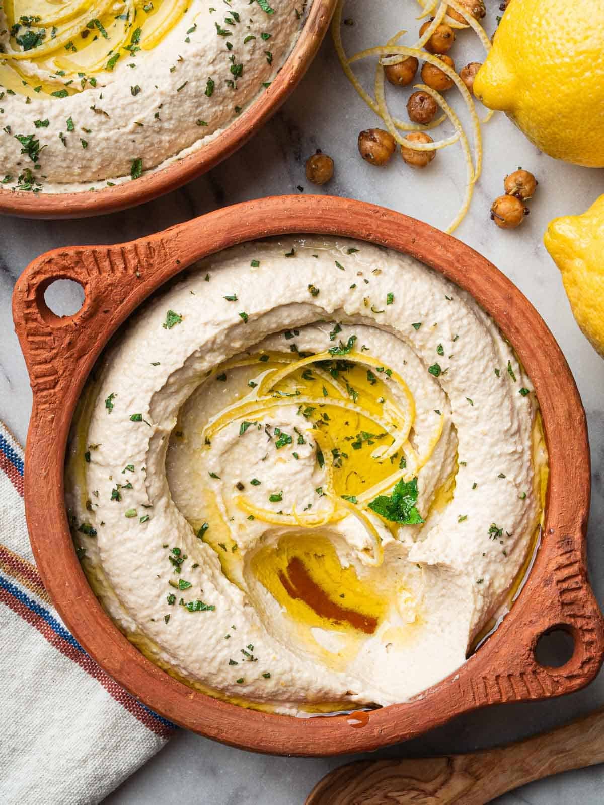 Lemon hummus topped with a drizzle of olive oil and fresh mint, with a dollop scooped out.